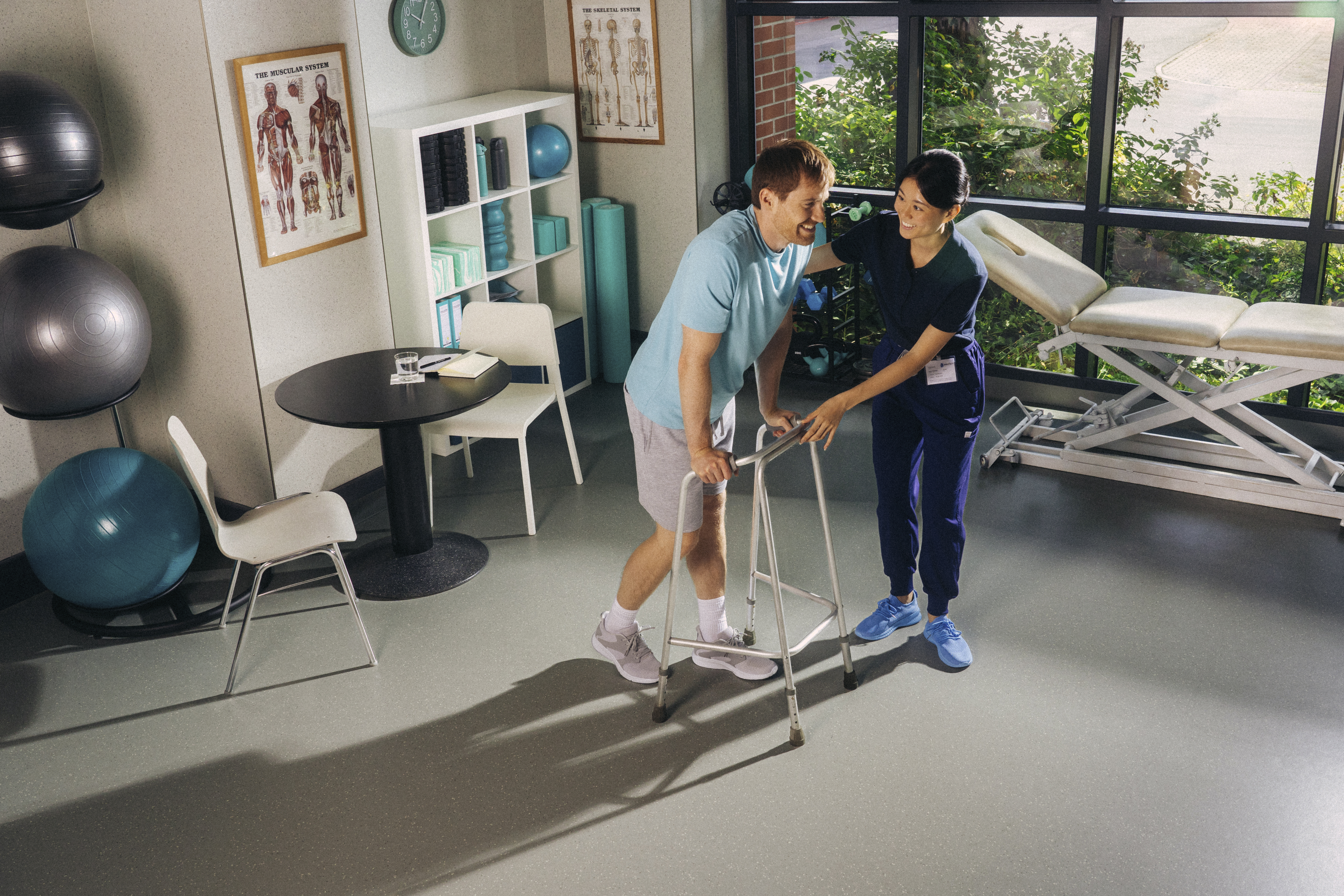 Physical therapy room with rubber flooring and therapist helping patient